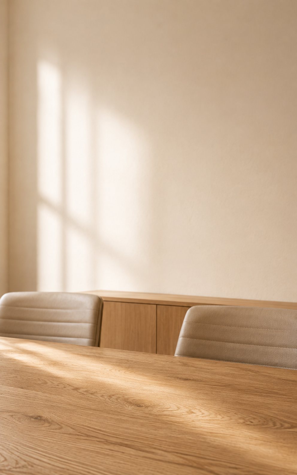 Canto de sala de reunião com mesa de madeira e duas cadeiras vazias